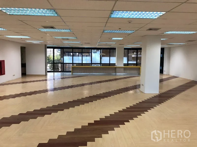 Office Space for rent in Bang Na, Bangkok - Spacious open-plan office with patterned wood floors, support columns and large windows.