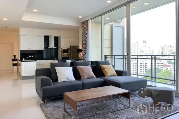 公寓 出租在Watthana, Bangkok - 宽敞起居区，L形沙发，推拉门通向阳台与城市景观。