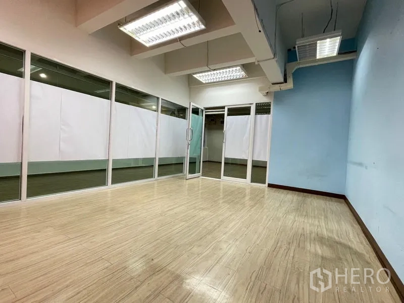 Office Space for rent in Ratchathewi, Bangkok - Bright corner office with wood‑laminate floors, glass partitions and double glass doors.