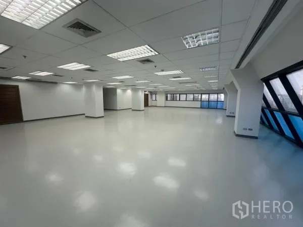 办公空间 出租在Phaya Thai, Bangkok - 宽阔办公内景，多根白色立柱、木门与长条斜面蓝色窗。