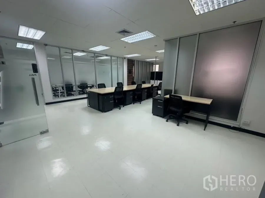 สำนักงาน ให้เช่า - พื้นที่สำนักงานแบบเปิด แสดงแถวโต๊ะทำงานและผนังกระจกฝ้า