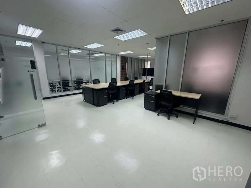 สำนักงาน ให้เช่า - พื้นที่สำนักงานแบบเปิด แสดงแถวโต๊ะทำงานและผนังกระจกฝ้า