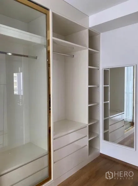 Condominium for rent in Khlong Toei, Bangkok - Built-in wardrobe with gold-trimmed sliding glass doors, drawers, and a full-length mirror.