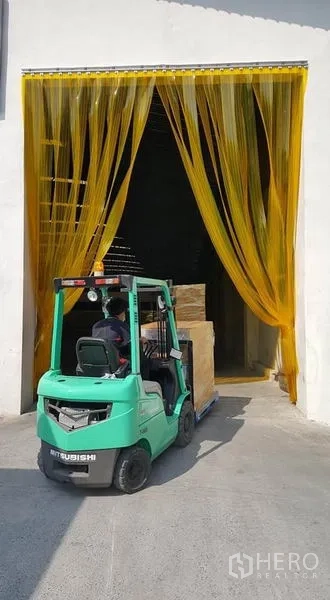Warehouse for rent or sale - Loading bay with yellow PVC strip curtains and a forklift moving palletized goods.