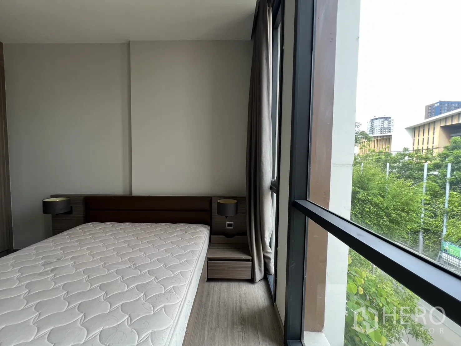 คอนโด for rent in Watthana, Bangkok - มุมห้องนอนหน้าต่างสูงและโต๊ะหัวเตียงมองเห็นแนวต้นไม้