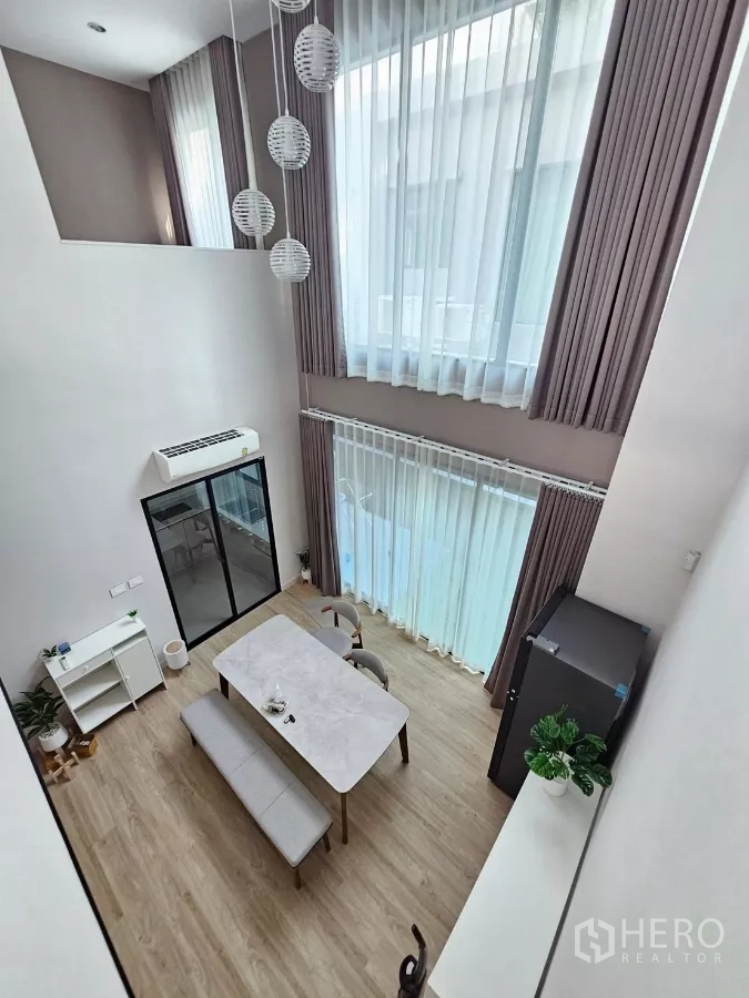 Townhouse for rent in Saphan Sung, Bangkok - Double-height dining and living area with full-height curtains and spherical pendant lights.