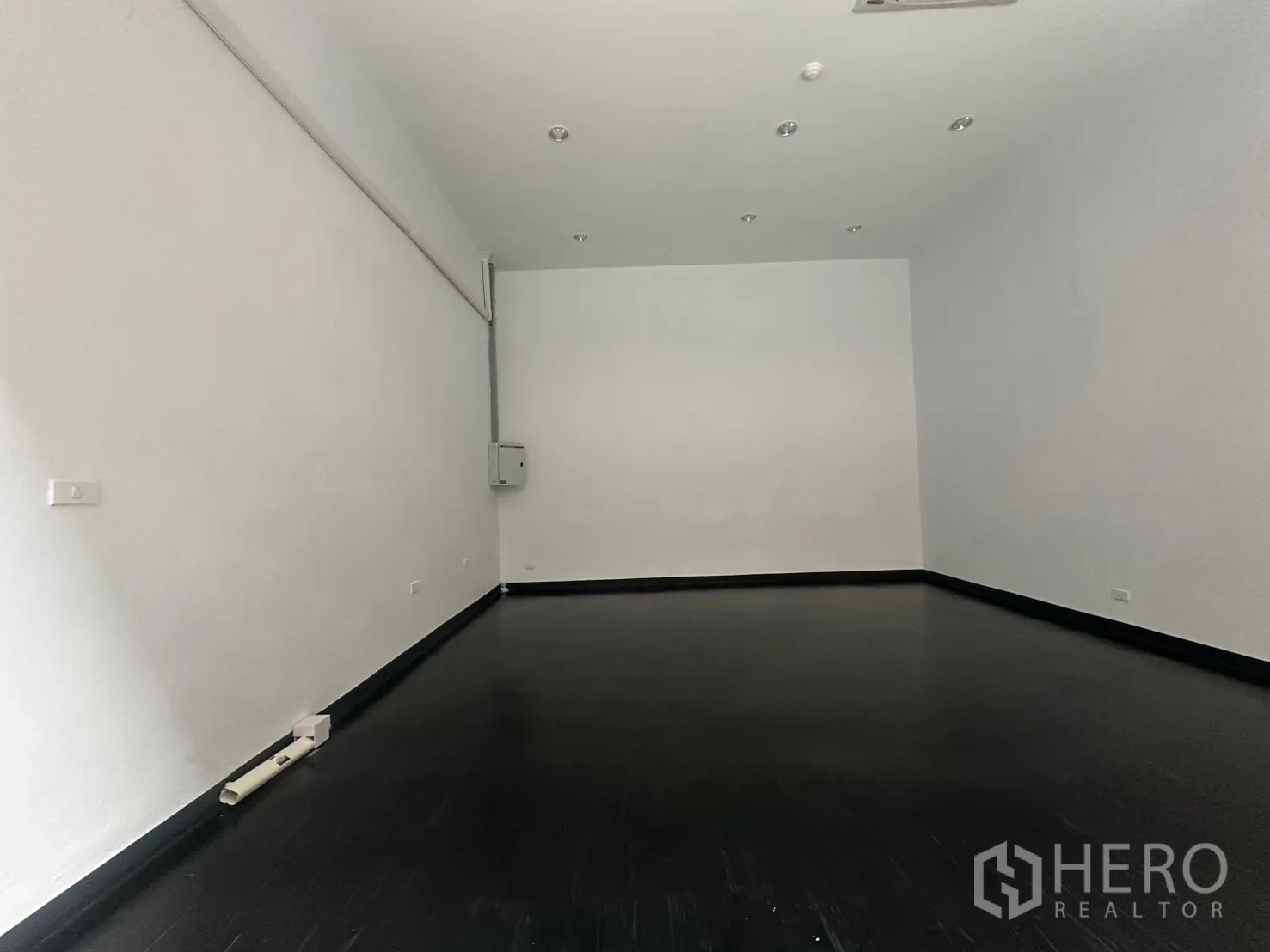 พื้นที่ขายของ for rent in Watthana, Bangkok - พื้นที่ภายในค้าปลีกผนังสีขาว พื้นสีเข้ม ไฟดาวน์ไลท์ และตู้ควบคุมไฟ