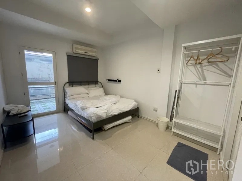 Home Office for rent or sale in Watthana, Bangkok - Air-conditioned bedroom with double bed, sliding balcony door and open clothes rack.