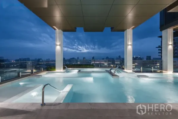 Condominium for sale in Watthana, Bangkok - Rooftop infinity pool with city skyline views at dusk and a covered deck.