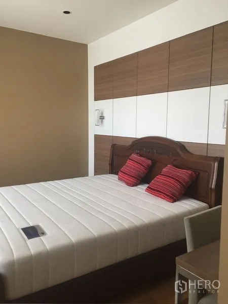 Condominium for rent - Second bedroom with paneled headboard wall, queen bed, and red accent pillows.