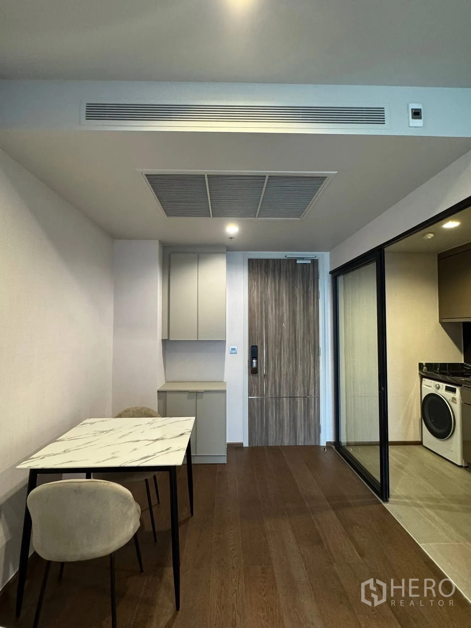 Condominium for rent in Khlong Toei, Bangkok - Compact dining area and entry with marble-top table and storage.