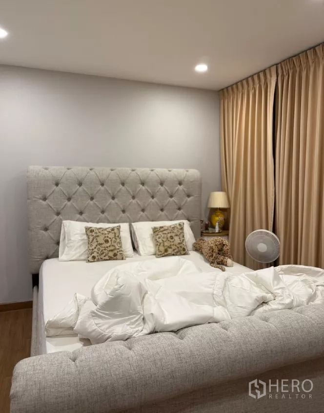 Detached House for rent or sale in Saphan Sung, Bangkok - Master bedroom with a tufted upholstered bed and warm curtains.