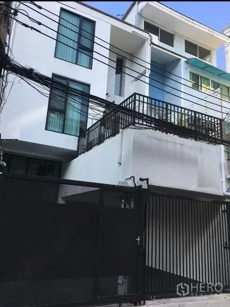 ทาวน์เฮาส์ ให้เช่าในBang Rak, Bangkok - ด้านหน้าทาวน์เฮ้าส์สีขาวสมัยใหม่ มีระเบียงและที่จอดรถพร้อมรั้วรักษาความปลอดภัย