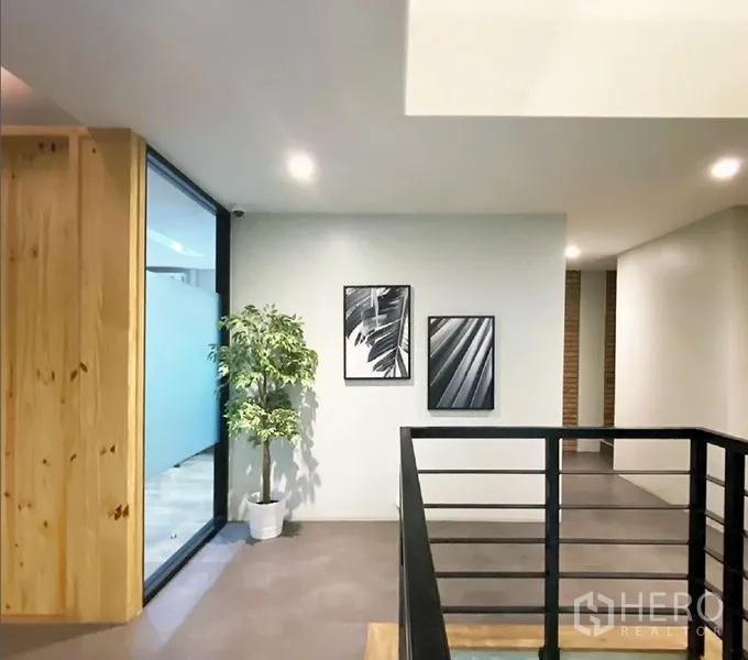 Office Space for rent in Bang Rak, Bangkok - Landing with framed artwork, a potted tree, and railing outside a glass-walled office.