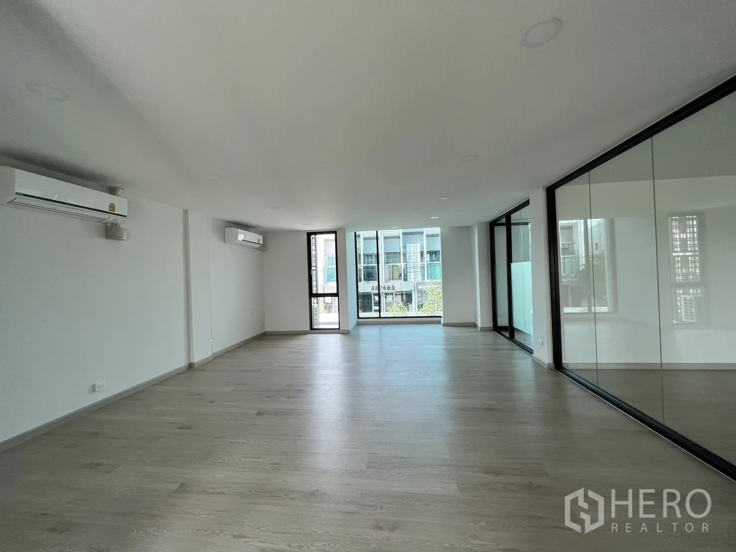 Home Office for rent in Bang Phli, Samut Prakan - Long open‑plan office with air‑conditioning and balcony access at the far end.
