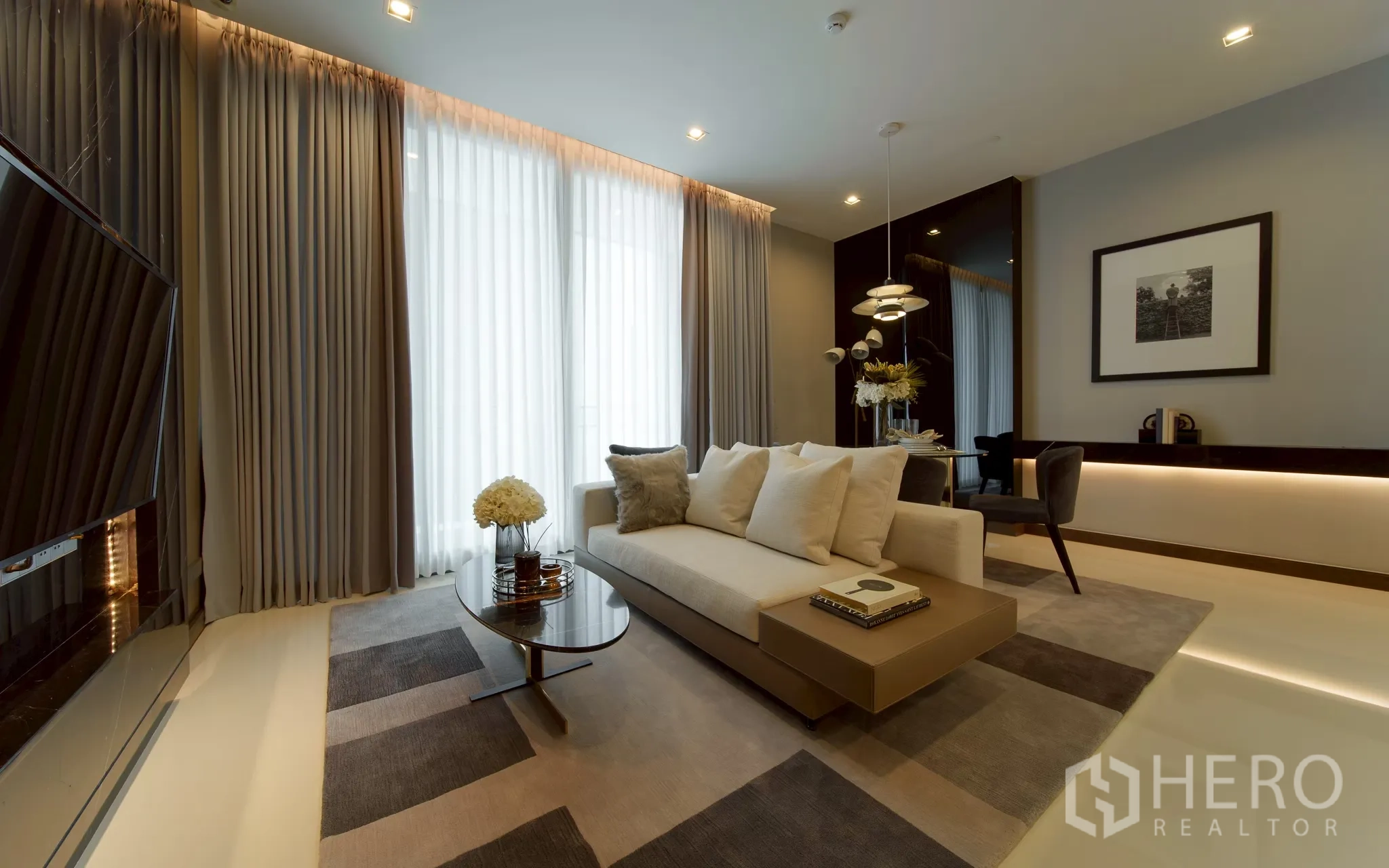 公寓 for sale in Khlong Toei, Bangkok - 现代客厅与餐区，米色沙发、茶几、落地窗帘、吊灯、电视墙与柔和氛围照明。