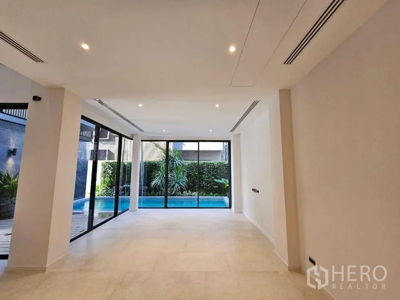 Detached House for rent in Wang Thonglang, Bangkok - Spacious open room with recessed lighting and full-height windows to the pool.