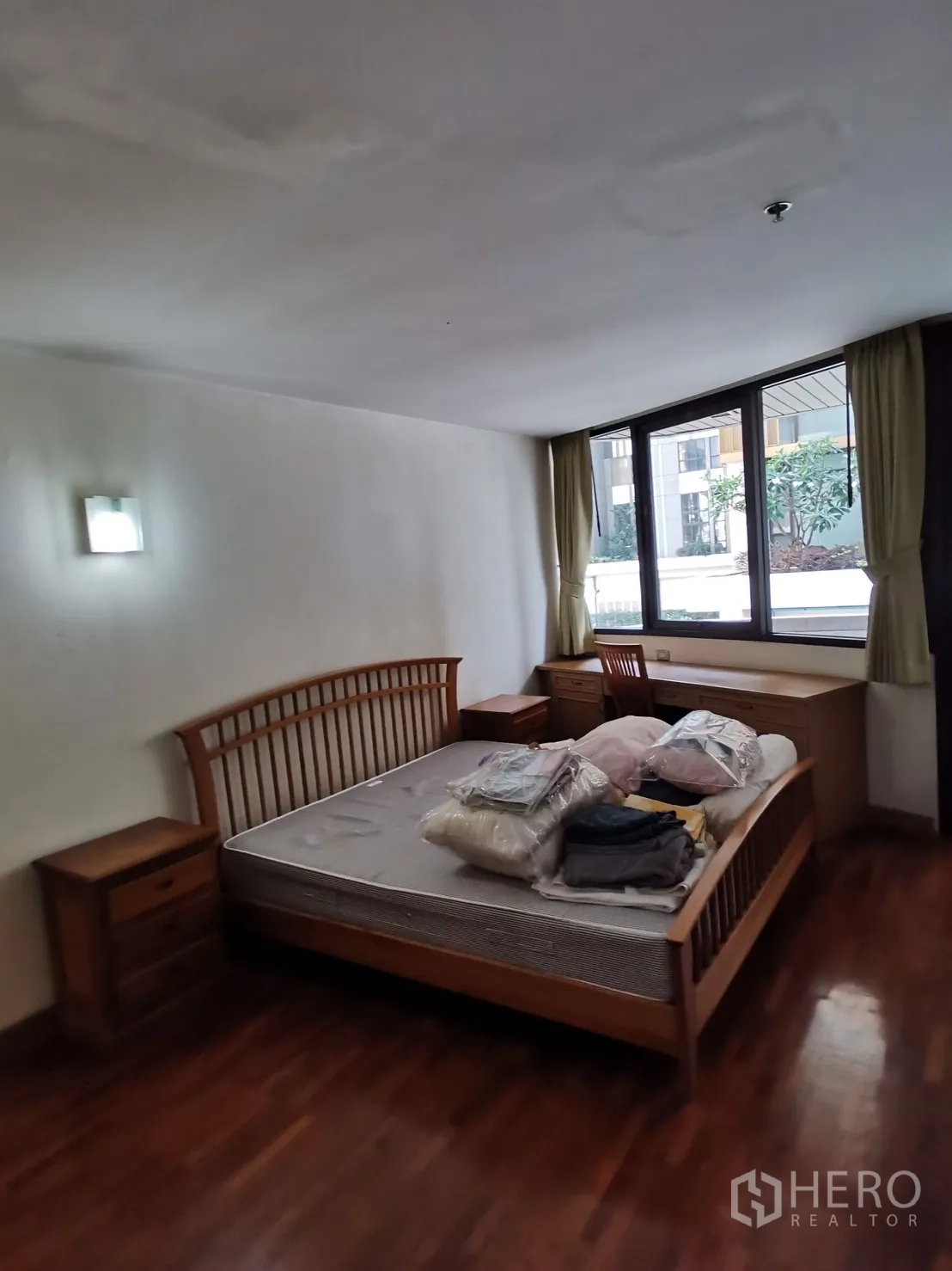公寓 出租在Pathum Wan, Bangkok - 明亮卧室，木质床架与床头柜，大窗朝向内院景观。