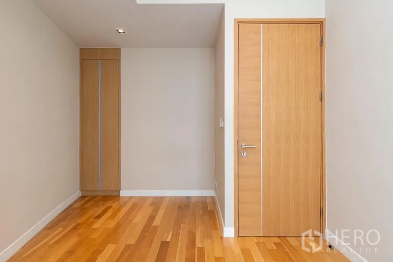Condominium for rent in Khlong Toei, Bangkok - Minimalist hallway with wood flooring, built-in closet, and interior door.