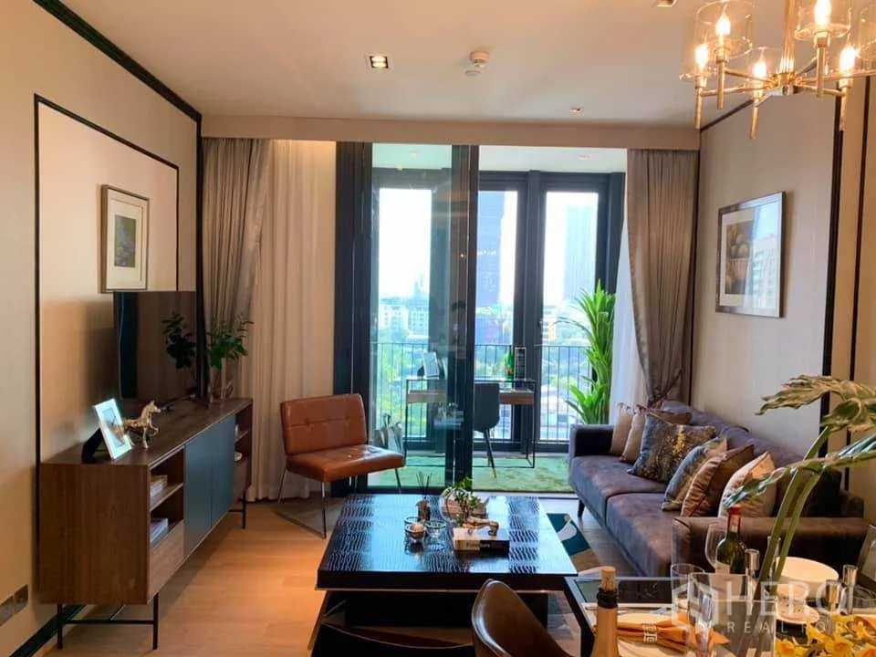 Condominium for rent in Khlong Toei, Bangkok - Living room opening to a balcony with city skyline views and abundant daylight.