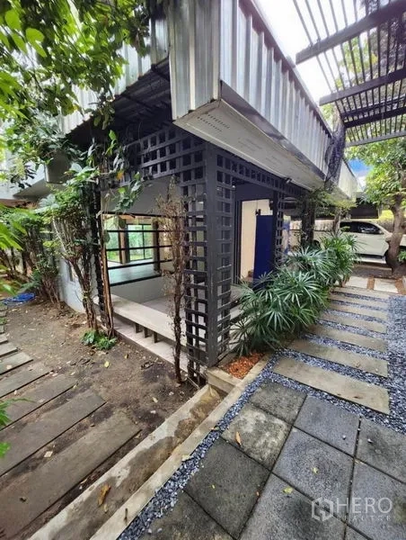 Home Office for rent in Lat Phrao, Bangkok - Modern exterior corner with lattice columns, greenery and stone paths in an industrial style façade.