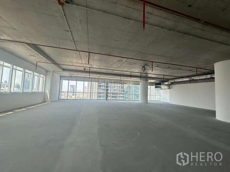 办公空间 出租在Sathon, Bangkok - 开放式办公室，混凝土地面与大片玻璃，远眺曼谷天际线，近BTS Saint Louis。