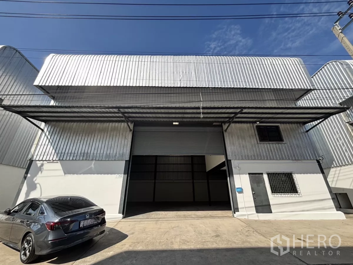 货栈 出租在Lat Krabang, Bangkok - 金属外墙仓库外观，超大卷闸门与遮雨装卸区，前方可停车