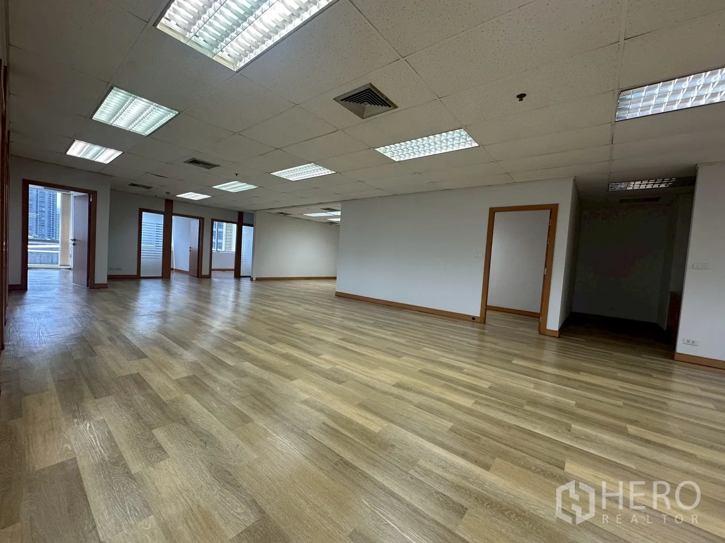 Office Space for rent - Open workspace leading to private rooms and a wall of windows providing natural light.