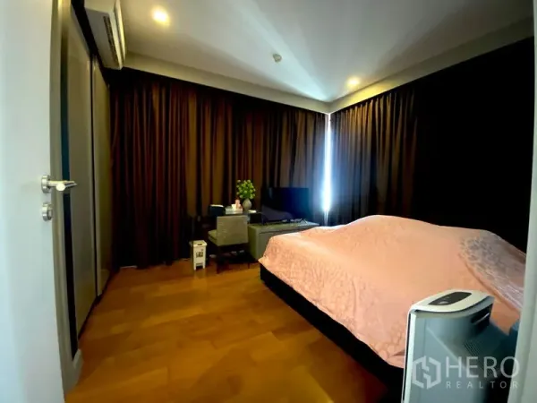 Condominium for rent in Bang Rak, Bangkok - Master bedroom with wood floors, dark curtains, a work desk and TV.