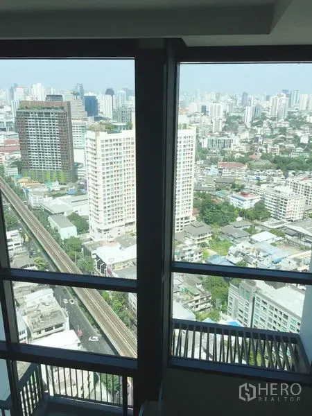 Condominium for rent in Khlong Toei, Bangkok - High-rise window view of Bangkok skyline with the Sukhumvit BTS track visible below.
