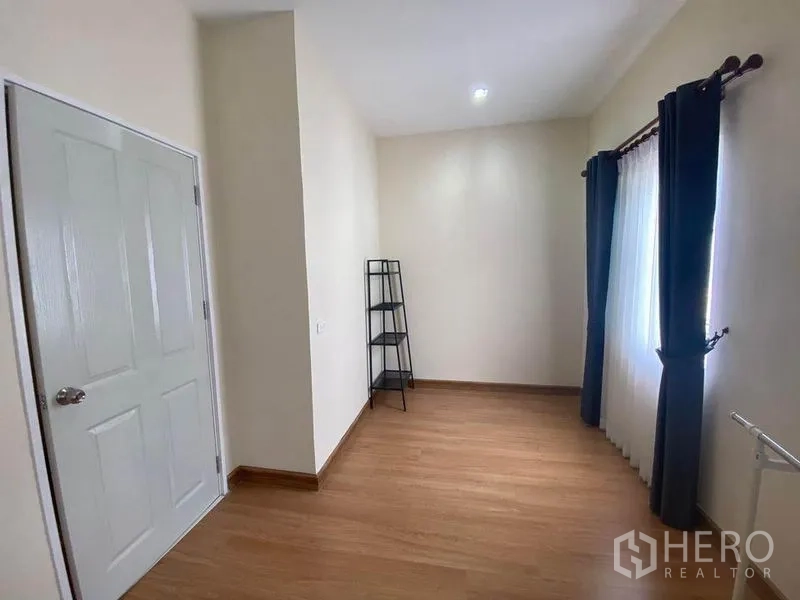 Townhouse for sale in Saphan Sung, Bangkok - Spare room or third bedroom with windows, curtains and a slim black shelf.