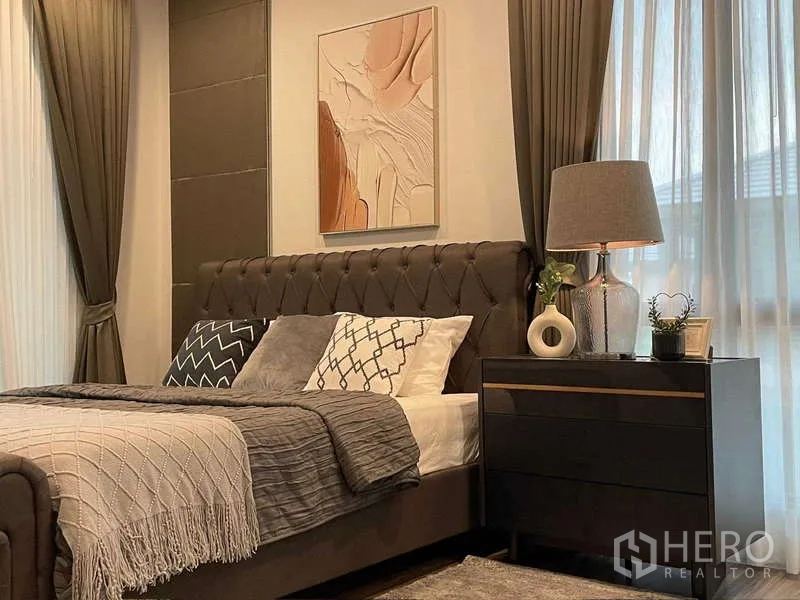 Detached House for rent in Bang Kapi, Bangkok - Cozy bedroom corner with tufted headboard, bedside table and wall art.