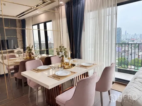 Condominium for rent in Watthana, Bangkok - Dining area by the balcony with gold accents and city outlook.