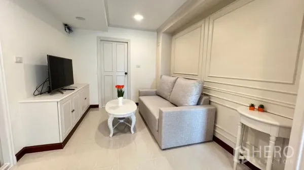 Condominium for rent in Phra Khanong, Bangkok - Cozy living room with a light gray sofa, TV console, and recessed lighting.