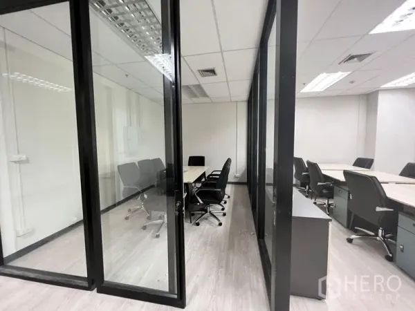 Office Space for rent in Sathon, Bangkok - Glass-partitioned meeting room with a long table and black swivel chairs in a modern office.