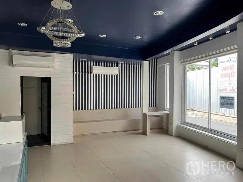 Retail Space for rent in Watthana, Bangkok - Bright retail interior with tiled floors, navy ceiling, striped feature wall, air conditioning and large street‑facing windows.