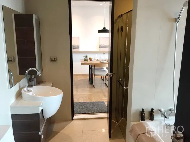 公寓 出售在Watthana, Bangkok - 现代化浴室，带淋浴与挂墙式洗手盆，门外通向餐区。