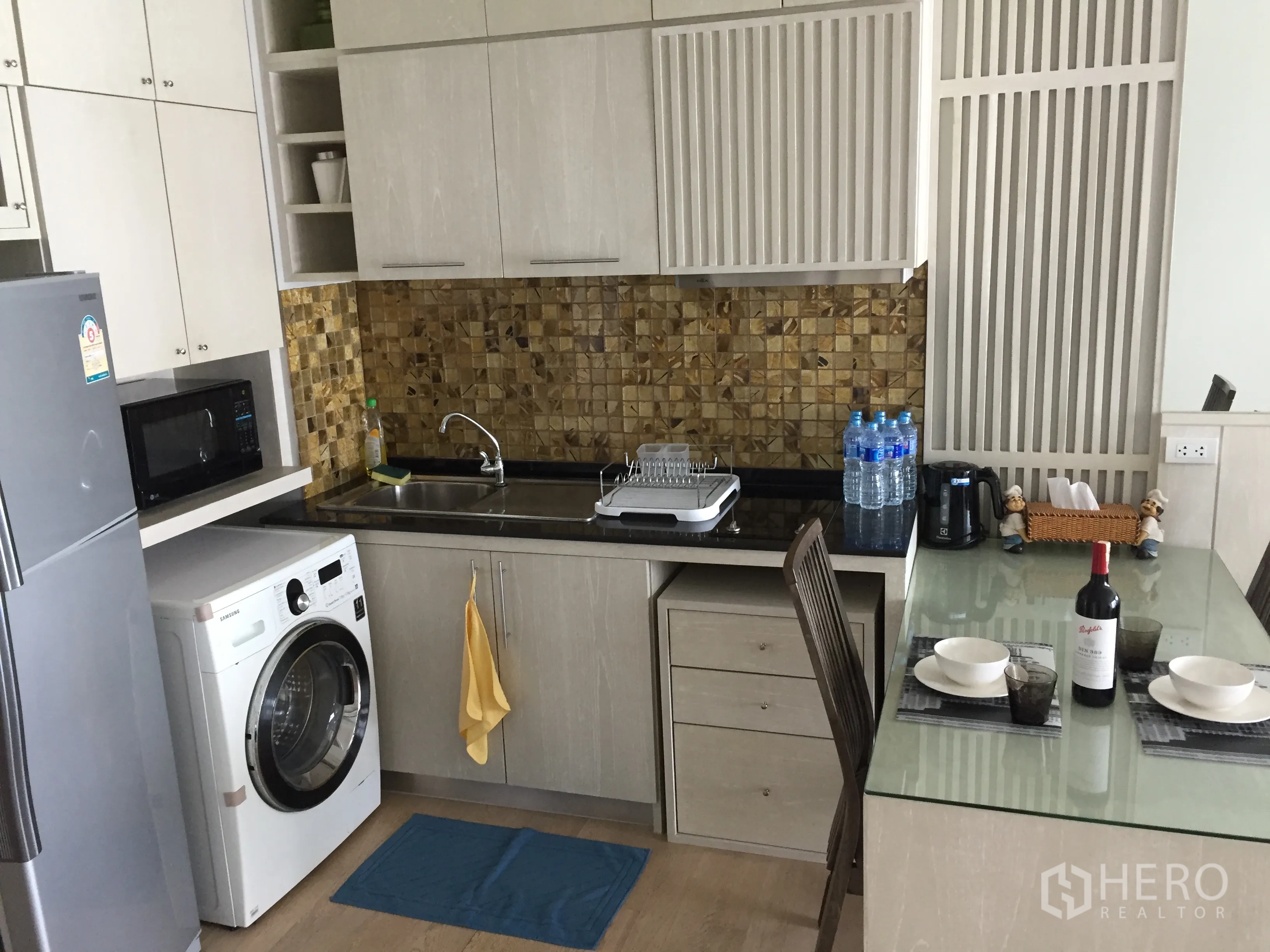 公寓 出租在Bangkok - 现代厨房，马赛克墙面，水槽、微波炉、冰箱、洗衣机与玻璃餐桌。