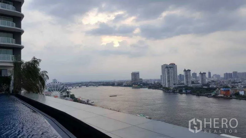 Condominium for rent in Bang Kho Laem, Bangkok - Infinity-edge pool overlooking the river under a cloudy sky.