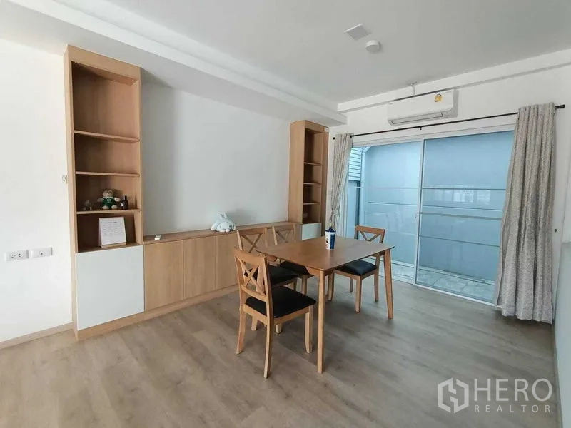 联排别墅 出租在Prawet, Bangkok - 餐区配木质餐桌椅、内置柜体与推拉门通向侧露台。