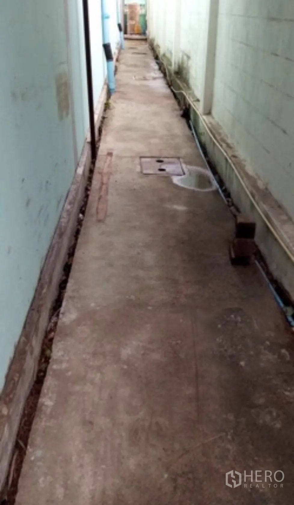 Warehouse for rent in Pak Kret, Nonthaburi - Narrow side service walkway beside the building with drainage covers.