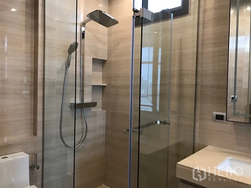 公寓 出租或出售在Watthana, Bangkok - 现代浴室，玻璃淋浴间与米色瓷砖，配雨淋花洒。