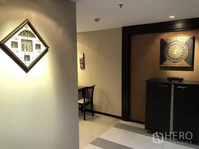 Condominium for rent in Khlong Toei, Bangkok - Entrance nook with display cabinet and framed artwork.