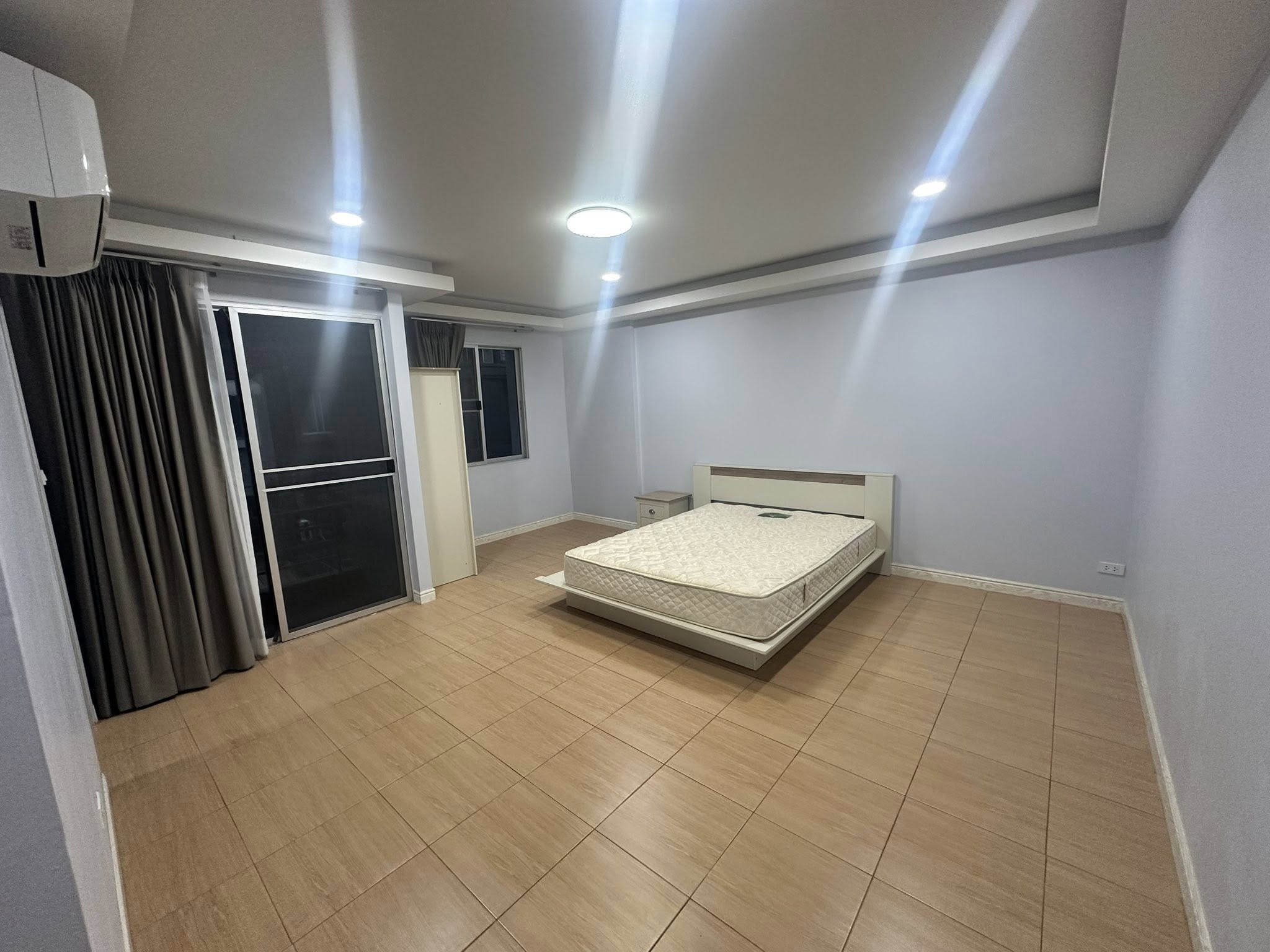 带办公室的家 出租在Wang Thonglang, Bangkok - 大卧室，木纹地砖，带床、阳台推拉门与窗帘。
