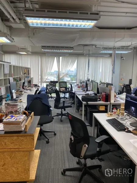 Office Space for rent in Khlong Toei, Bangkok - Bright workspace with multiple desks, ceiling lights, and city views through wide windows.