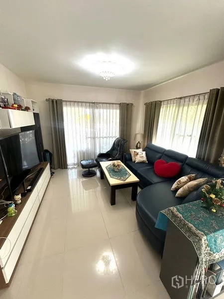 Detached House for rent in Bang Phli, Samut Prakan - Family lounge with TV wall unit, blue sectional sofa, and glossy tiled floors.