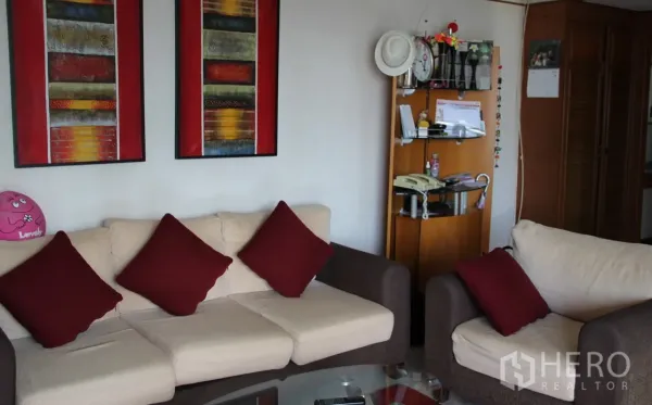Condominium for rent in Khlong Toei, Bangkok - Bright lounge featuring a sofa set, glass coffee table, and wooden shelving unit.