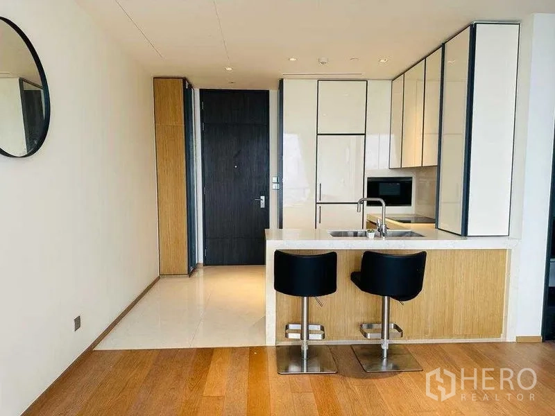 Condominium for rent in Khlong Toei, Bangkok - Contemporary kitchen with island sink, built-in cabinets, and bar seating.