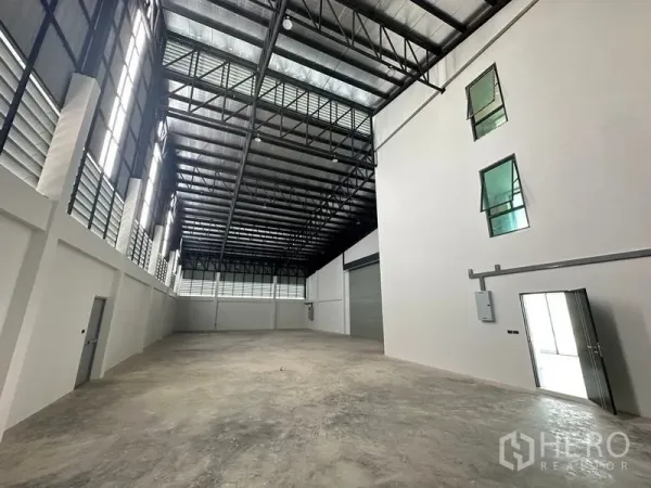 Warehouse for sale in Lam Luk Ka, Pathum Thani - Spacious warehouse interior with steel truss roof, ventilation louvers and polished concrete floor.