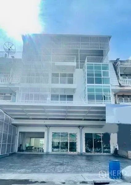 Home Office for rent or sale in Bang Kapi, Bangkok - Front facade of a modern 4.5‑storey home office with large glass windows and a covered parking bay.